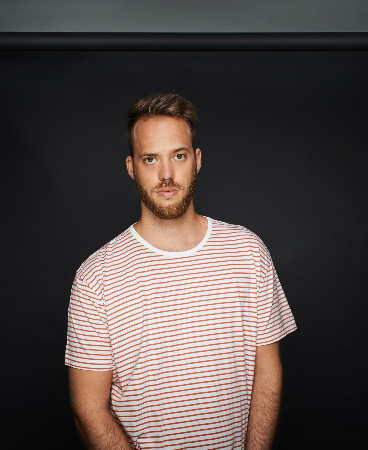 junger Mann bestreiftes grauer Hintergrund Studio streifen lächelnd Jörn Strojny